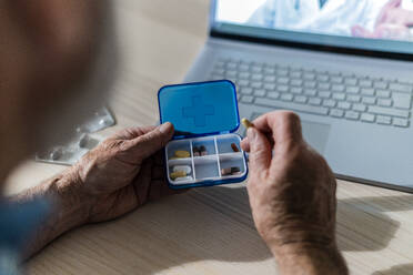 Mann im Ruhestand hält Pillenschachtel bei Videogespräch mit Arzt zu Hause - GIOF14136