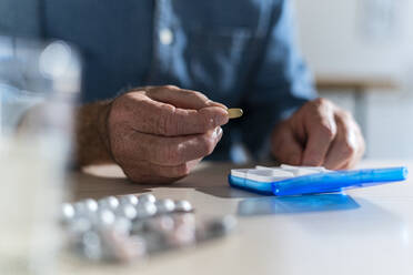 Man holding medicine by pill box at home - GIOF14138