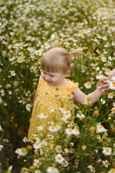 Blondes Mädchen hält die Hand der Mutter inmitten von Blumen auf einer Wiese - SSGF00254