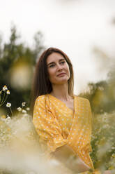 Contemplating woman in yellow dress at meadow - SSGF00259