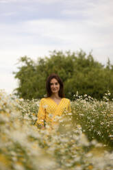 Smiling woman standing amidst flowers on meadow - SSGF00263