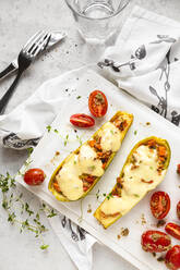 Gefüllte Zucchini mit Kirschtomaten und Käse auf dem Tisch serviert - FLMF00685