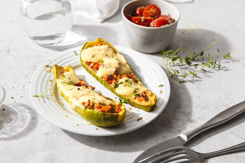 Gefüllte Zucchini mit Käse und Kirschtomaten auf dem Tisch - FLMF00688