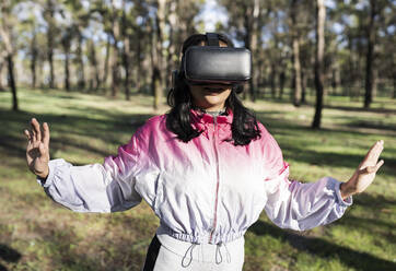 Woman with virtual reality headset gesturing at park - JCCMF04566