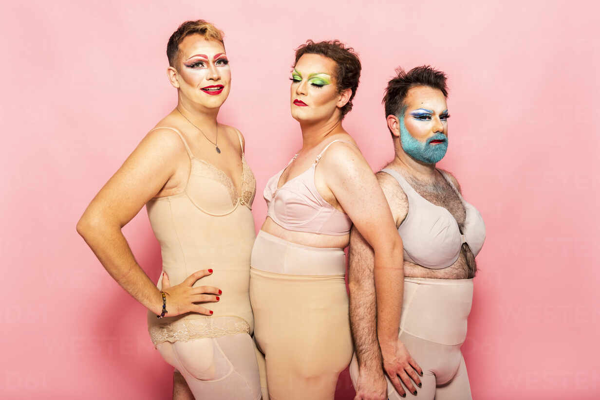 Drag queens in shapewear by pink background stock photo