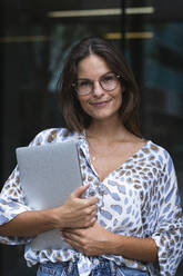 Geschäftsfrau mit Brille und Laptop vor dem Büro - PNAF02536