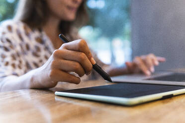 Geschäftsfrau mit digitalisiertem Stift und Laptop in einem Cafe - PNAF02542