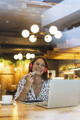 Glückliche Geschäftsfrau, die in einem Café mit ihrem Mobiltelefon spricht - PNAF02557