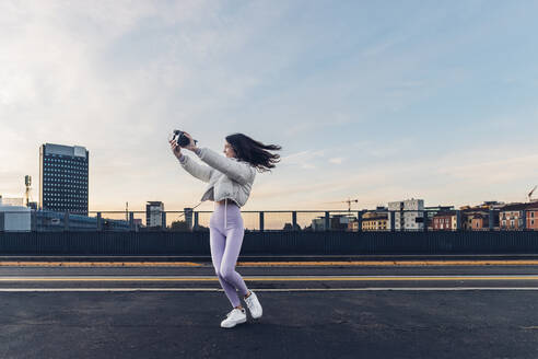 Influencer filmt durch Kamera auf der Straße bei Sonnenuntergang - MEUF04714