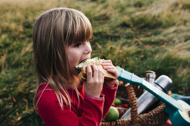 Blondes Mädchen isst Sandwich im Gras - ASGF01670