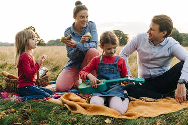 Lächelnde Eltern sitzen mit ihren Töchtern auf einer Picknickdecke - ASGF01686