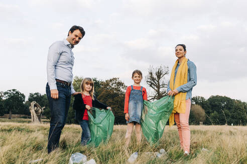 Familie mit Müllsäcken beim Aufräumen im Park - ASGF01693