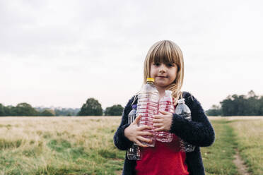 Mädchen mit Plastikflaschen im Park stehend - ASGF01707