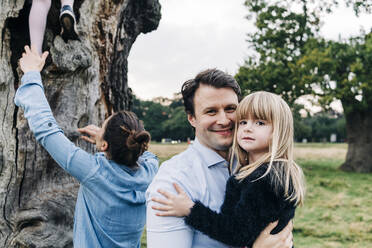 Smiling father carrying daughter in park - ASGF01712