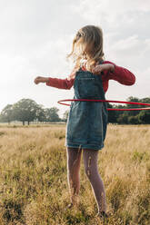 Girl playing with hula hoop in park at weekend - ASGF01725