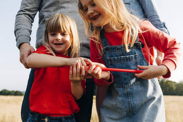 Glückliche Schwestern spielen mit Hula-Hoop-Reifen im Park - ASGF01739