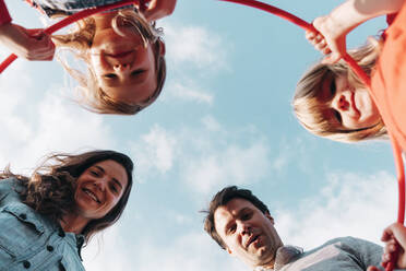 Happy family with hula hoop in front of sky - ASGF01740