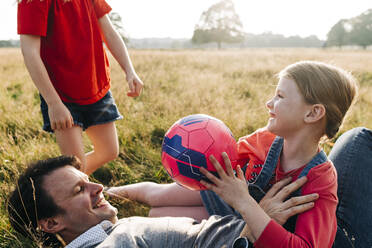 Cheerful father playing with daughters in park - ASGF01745