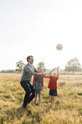 Vater und Töchter spielen mit Ball im Park - ASGF01748