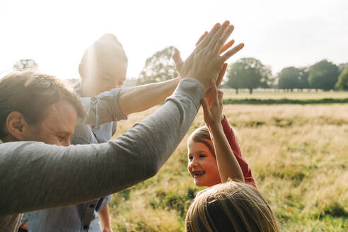 Glückliche Familie beim High-Five im Park am Wochenende - ASGF01754