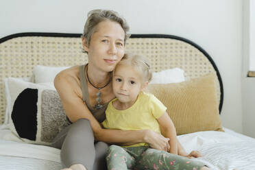 Mother sitting with daughter on bed at home - SEAF00131