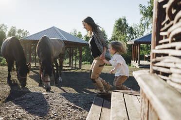 Playful mother and daughter running at horse farm - SEAF00137