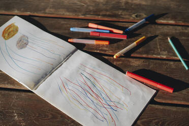 Book and colorful pen on wooden bench - SEAF00145