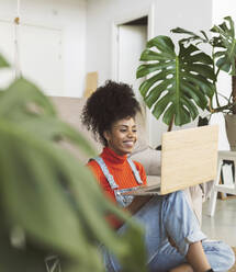 Happy woman talking on video call through laptop at home - JCCMF04587