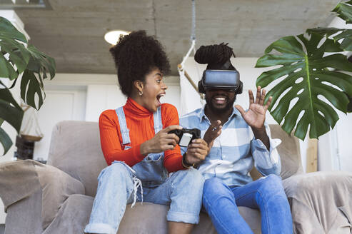Cheerful couple playing video game at home - JCCMF04594