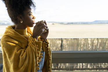 Woman having coffee and looking out of window at home - JCCMF04620