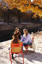 Lächelnde Geschäftsfrauen diskutieren im Herbst Park in sonnigen Tag - DAWF02317