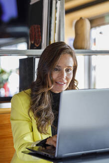 Lächelnde Geschäftsfrau mit Laptop in einem Café - IFRF01231