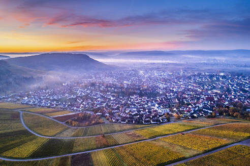 Germany, Baden-Wurttemberg, Korb, Drone view of vineyards and surrounding town at foggy autumn dawn - STSF03109