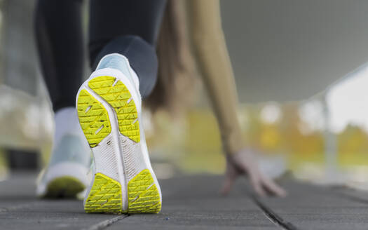 Sohle eines Sportschuhs einer jungen Frau, die sich vor dem morgendlichen Joggen im Freien dehnt - STSF03116