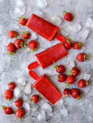 Overhead of strawberry popsicles with berries and ice on concrete. - CAVF95220