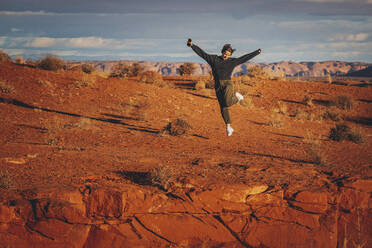 A woman with a phone is jumping in Monument Valley, Arizona - CAVF95244