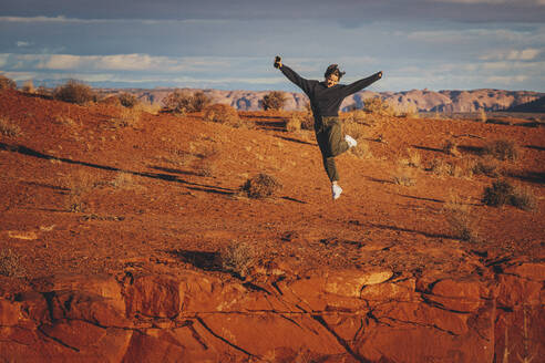Eine Frau mit einem Telefon springt im Monument Valley, Arizona - CAVF95244