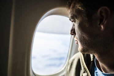 Man with beard looks out the window of an airplane. - CAVF95254