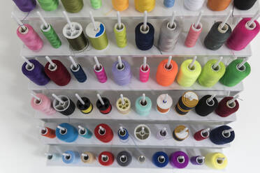 A large selection of colorful cotton thread reels arranged on spools. - CAVF95265