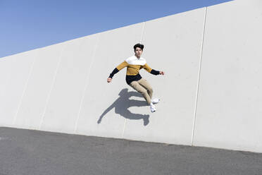 Junger Mann springt auf der städtischen Wand Hintergrund - CAVF95272