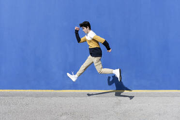 Junger Mann springt auf der städtischen Wand Hintergrund - CAVF95273