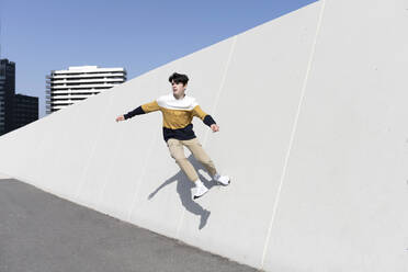 Young man jumping on the urban wall background - CAVF95276