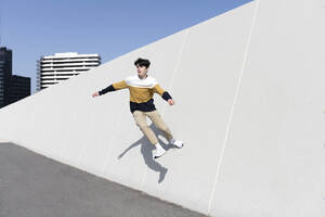 Junger Mann springt auf der städtischen Wand Hintergrund - CAVF95276