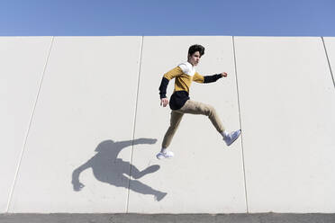 Young man jumping on the urban wall background - CAVF95278