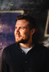 Portrait of happy smiling man standing against wall in city - CAVF95293