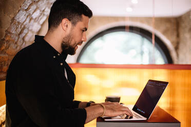 Konzentrierter Mann mit Laptop in einem Café - CAVF95295