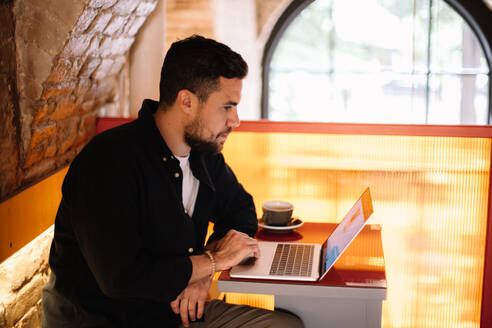 Konzentrierter Geschäftsmann mit Laptop in einem Café - CAVF95296