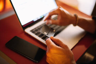 Mann benutzt Kreditkarte und Laptop beim Online-Shopping - CAVF95297