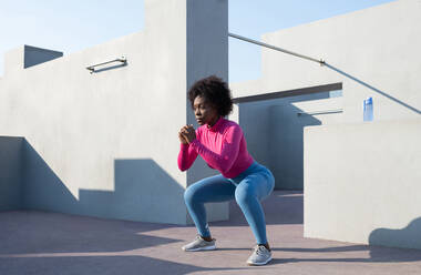 African American female athlete squatting - CAVF95316