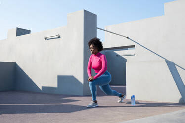 Afroamerikanische Sportlerin beim Longieren an einem sonnigen Tag - CAVF95318